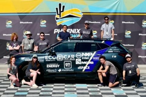 Group of students standing with a car with logos on it