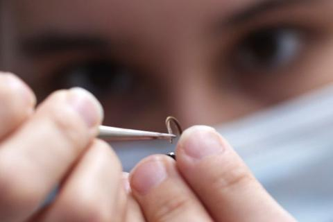 UW engineer Melanie Anderson carefully threads a moth antenna onto a circuit. The hair-like wires slide perfectly into the hollow tube of the antenna.