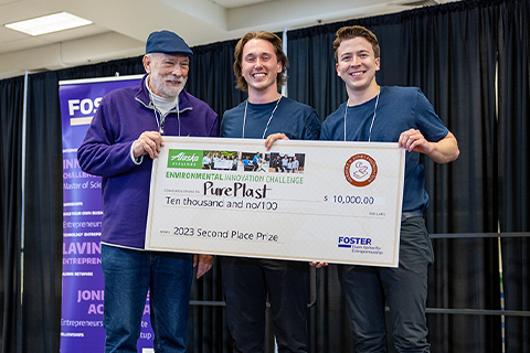 Three men holding a giant check award