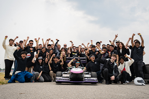 a group of people posing for a photo with a race car