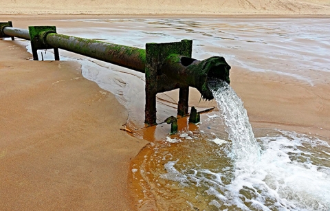 Water gushing out of a pipe on a beach