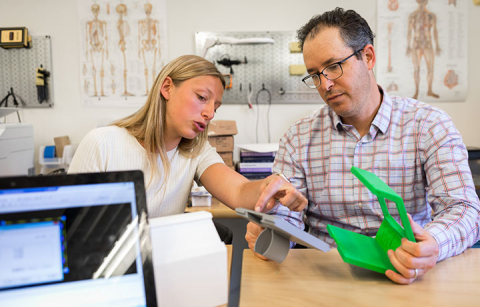 A faculty reviews a student's medical device prototype