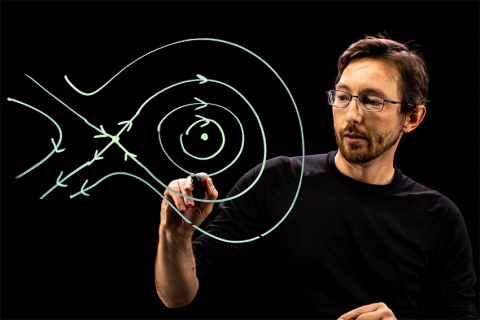 Professor Steve Brunton drawing lines with arrows on a lightboard
